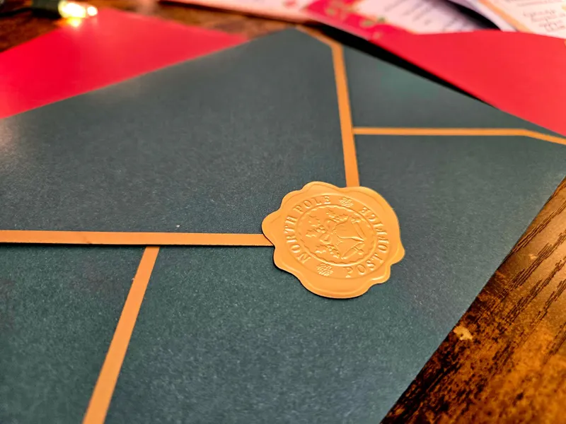 A green envelope closed with a gold wax seal